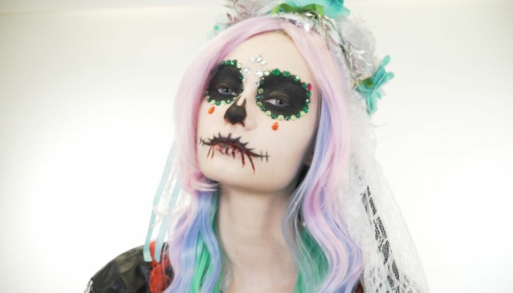 Kvinna sminkad som en glam skull inför halloween.