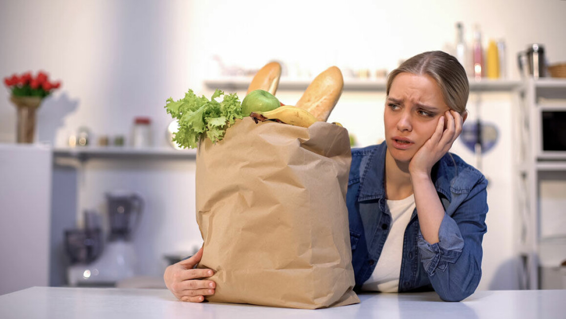 Kvinna suckar och tittar på en papperspåse med mat.