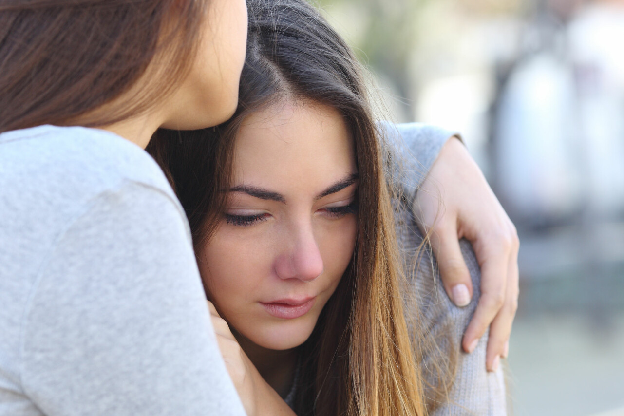 Kvinna tröstar tonåring i sorg.