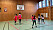 Kvinnor och barn spelar basket i en gympasal.