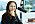 Porträttbild på Elin Samuelsson som sitter i en poddstudio med hörlurar på öronen och en stor mikrofon framför sig.
