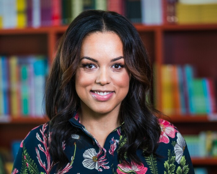 ”ju mer kunskap du har, desto ödmjukare behöver du vara när du kommunicerar men andra”, menar Elaine Eksvärd. Glad Elaine Eksvärd framför bokhyllor.