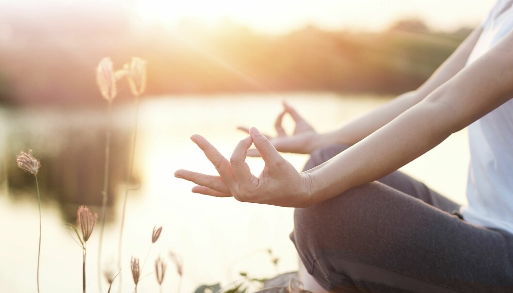 Kvinna gör yoga vid sjö, kanske för att lindra ibs.