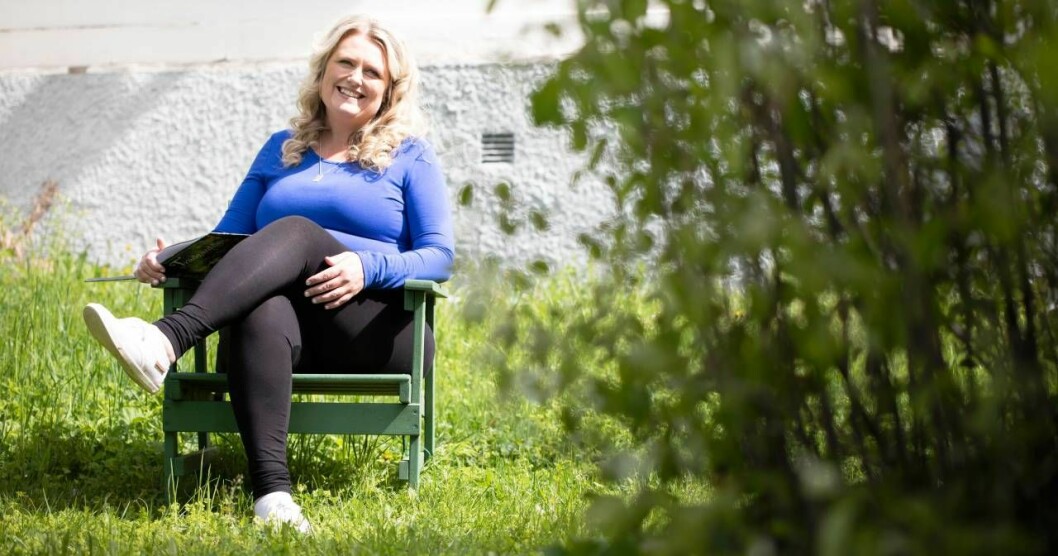 En leende Lindha sitter i sin solstol i trädgården. 