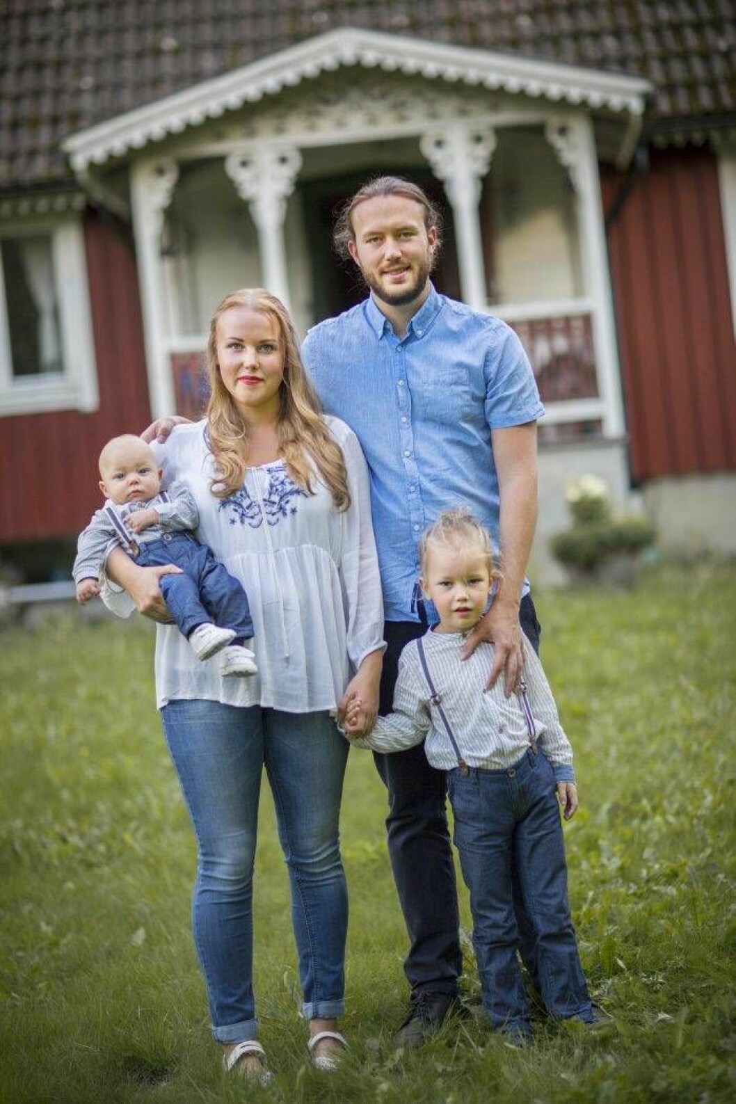 År 2018, när den här bilden togs, utökades den unga familjen och tre blev fyra. Då fick Linnea och Victor sitt andra barn och Vide blev storebror till Alve. Foto: Ewa Stackelberg Linnea Jonsson tillsammans med sin familj framför ett rött hus med vita knutar