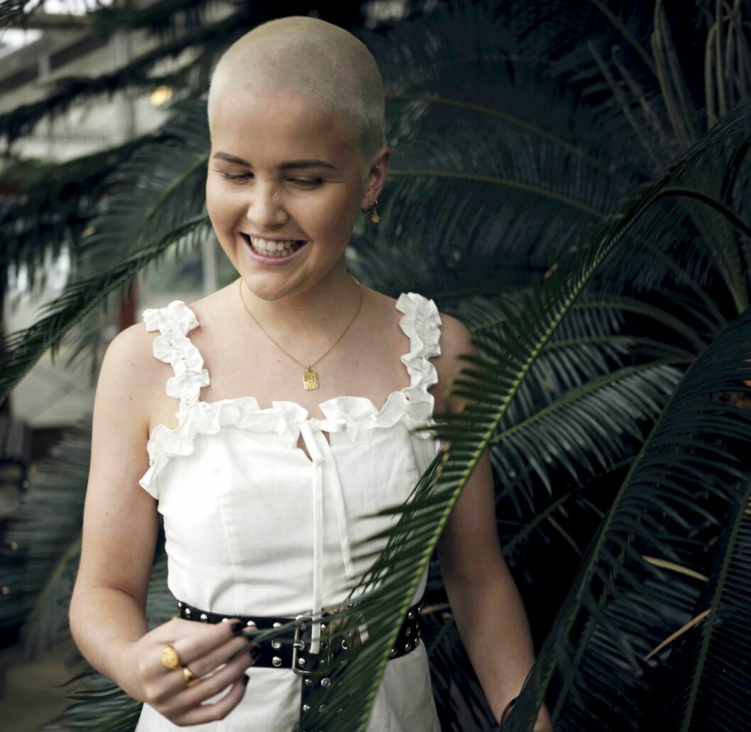 Linnea måste leva med sin sjukdom resten av livet, men säger att hon själv kan välja hur hon vill ha det. Foto: Håkon Jørgensen Linnea, som lever med autoimmun pankreatit, ler och tittar på ett blomblad