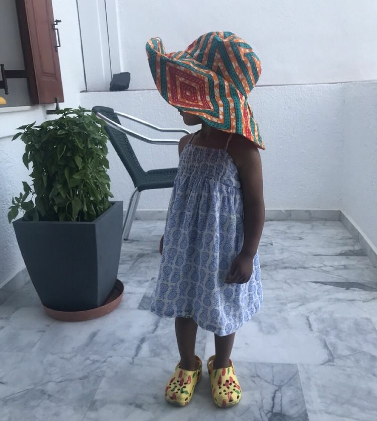 – Liv har ännu inte besökt Moçambique, men vi planerar att ta henne dit. Att känna familjen och kulturen man kommer ifrån tror jag kan vara en stor bekräftelse och försäkran. Liv står på en terass. Hon bär en blå sommarklänning och en mönstrad solhatt med huvudet vänt mot kameran.