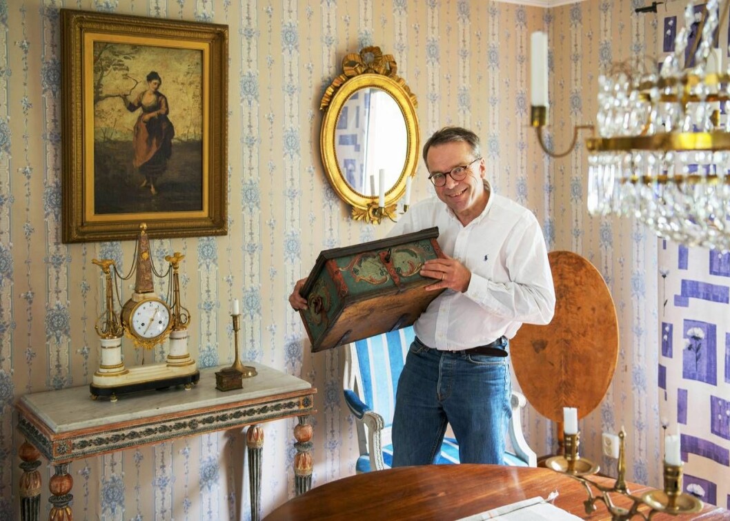Knut Knutson med ett skrin i famnen i ett antikt hem