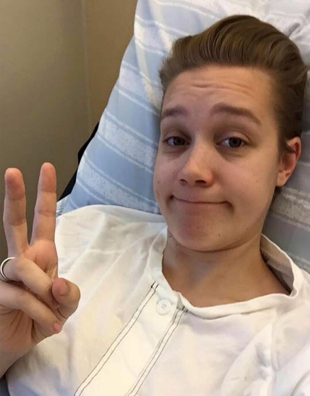 Lovisa blev inlagd på Sahlgrenska sjukhuset när äggen skulle sugas ut från äggledarna. Foto: Privat Äggdonatorn Lovisa ligger i en sjukhussäng och gör peace-tecken.