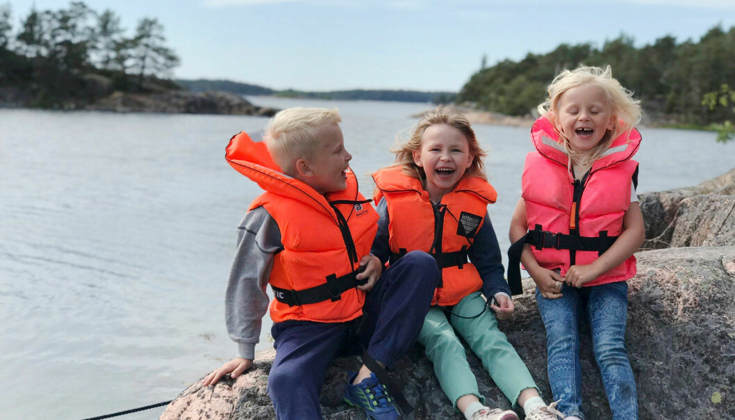 Luna med kusinerna Wilhem och Wilma. De har på sig flytvästar och sitter på en klippa vid vattnet.