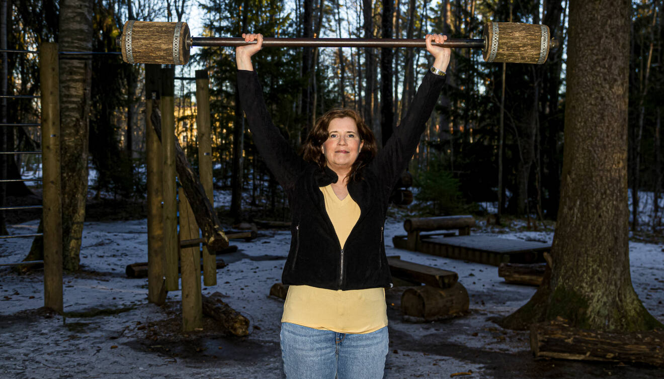 Maria Thysell lyfter en trä-skivstång i skogen på ett naturgym.