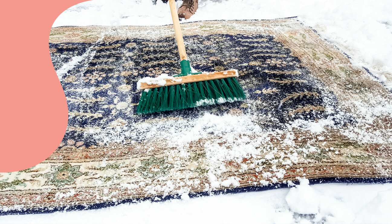 Städning av en matta i snön med en kvast.