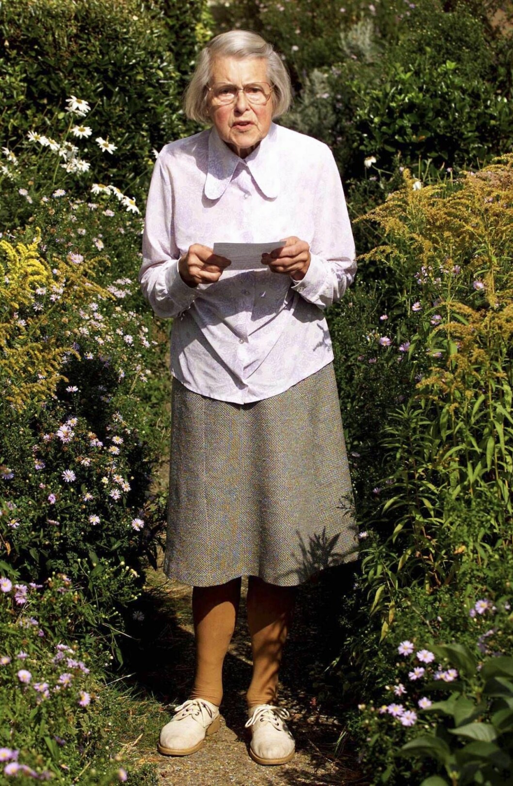Klädd i violett blus och tweedkjol läste hon upp sin handskrivna bekännelse hemma i trädgården. Foto: TT Melita i trädgården.
