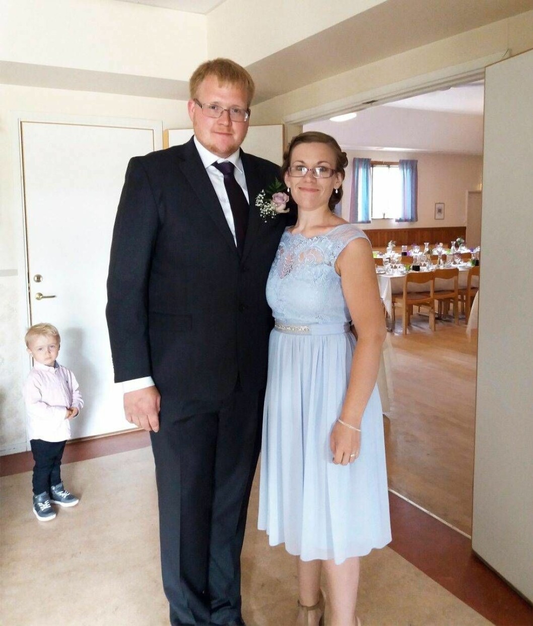 Ett ungt finklätt par står och håller om varandra.
