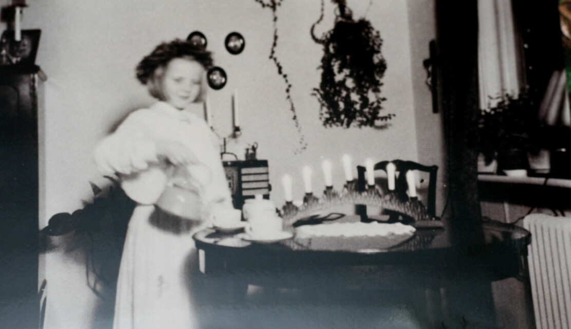 Elljusstakarna lyste upp Nancys hem när hon var barn. Nancy i lucialinne och krans på huvudet häller upp kaffe och på bordet står pappas elljusstake.