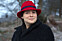 Natalia med ett litet leende i svart kappa och röd hatt.