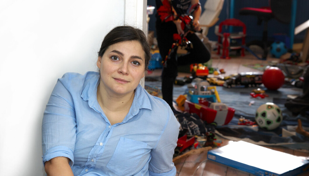 Natalia med litet leende och i bakgrunden leker sonen Alvar i sitt pojkrum.