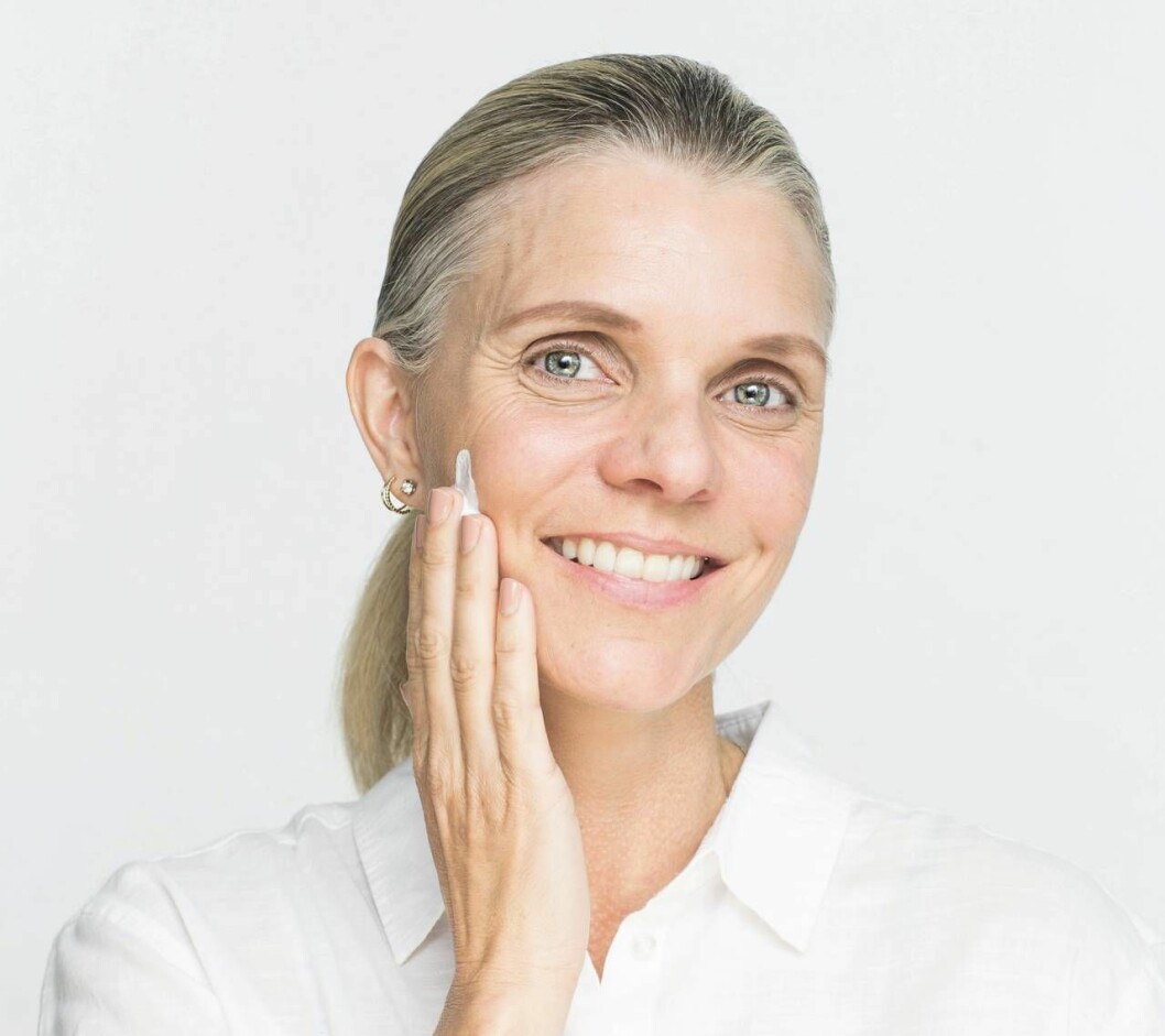 Att återfukta huden är bra om du vill att din makeup ska lägga sig i ett jämnt lager. Kvinna smörjer in huden med fuktcreme