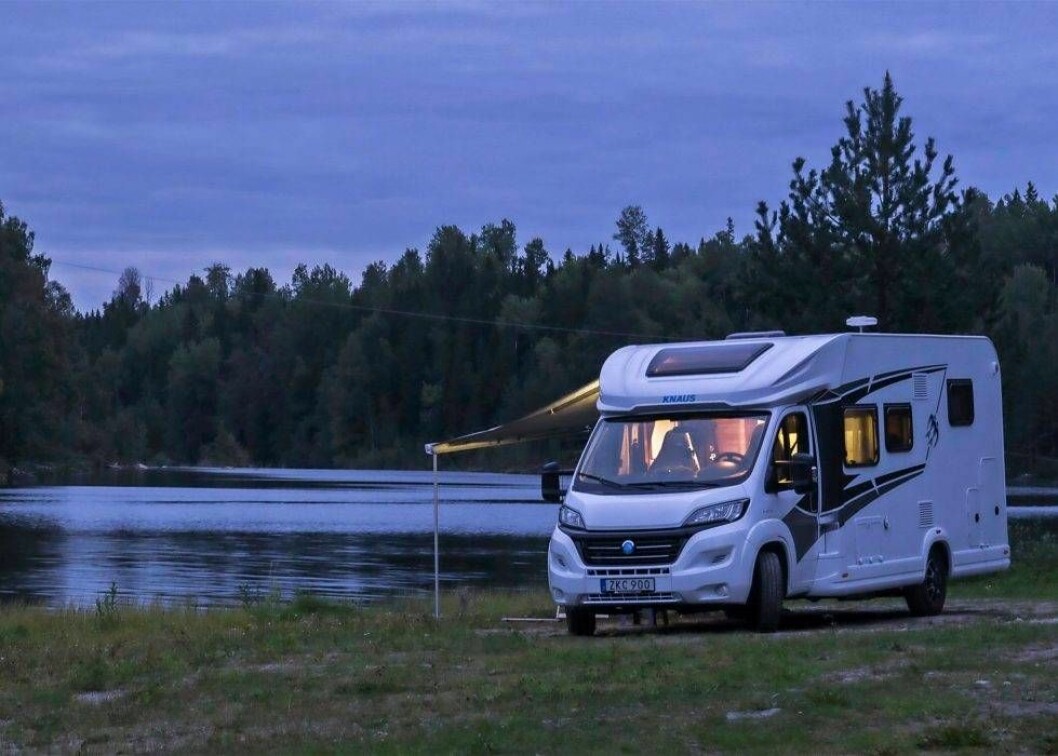 En husbil står vid en sjö på kvällen.