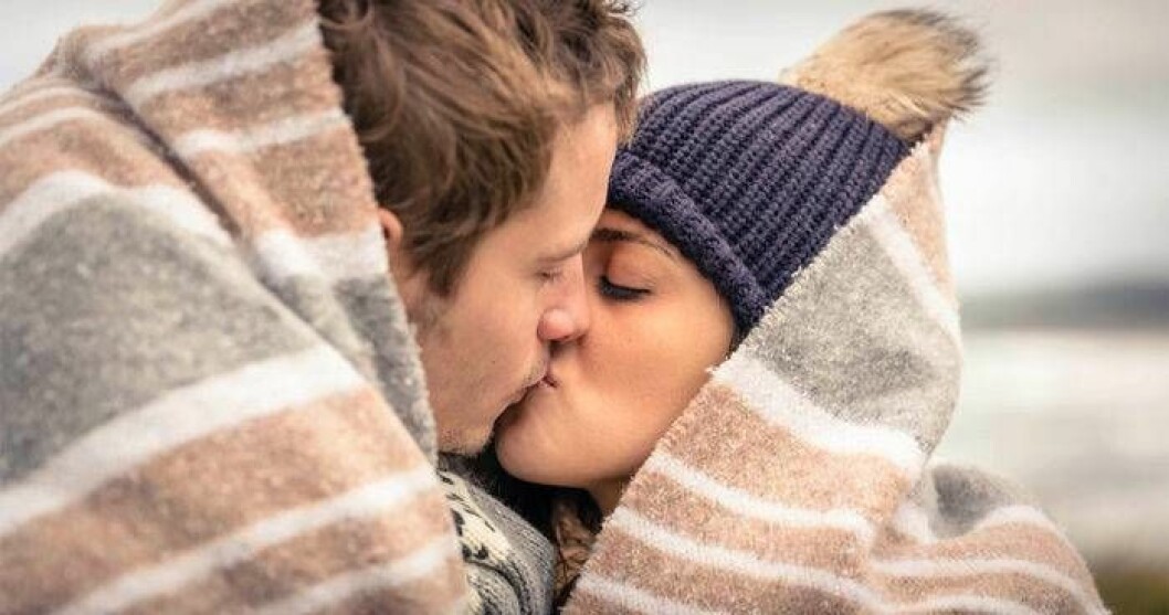 Tvillingen kan hitta kärleken i ett kulturellt sammanhang. Håll utkik! Foto: Shutterstock/IBL Ett kyssande par under en filt.