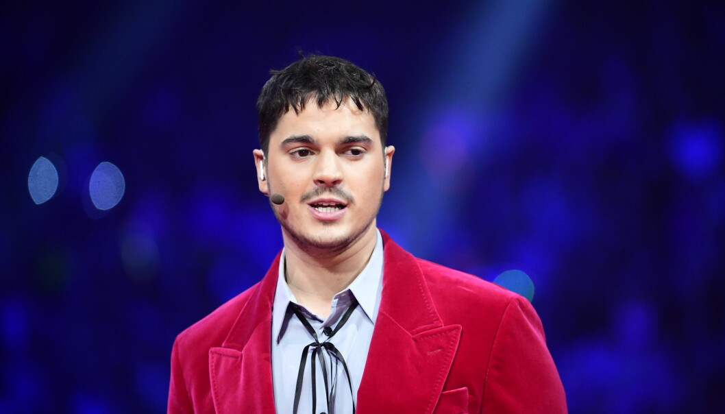 Oscar Zia, iklädd skjorta och röd kavaj, programleder Melodifestivalen.