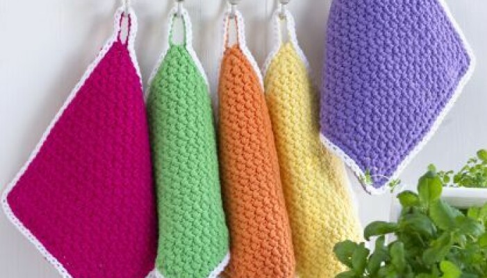Bild på hängande grytlappar i färgerna fuchsia, grön, orange, ljusgul och lila.