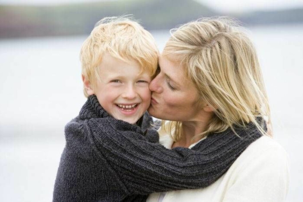 Mamma pussar sin son på kinden.