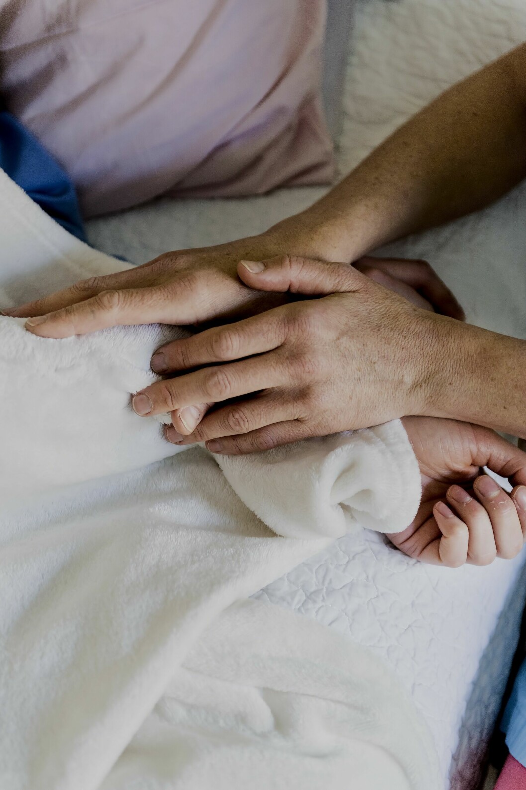 Petra känner att hon dras till de svåra stunderna. – I mötena får jag en chans att göra skillnad, och på så sätt bearbeta min egen historia, säger hon. Beröring i sjuksängen. Närbild på händer som rör den döendes händer och armar.