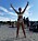 Pia Jensen står på stranden och sträcker upp händerna och ler. Hon har på sig en bikini och på magen syns hennes stomipåse.