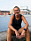 Pia Jensen sitter på kajen längs kanalen i Malmö. I bakgrunden syns gamla Kockums fabrik och byggnaden Gängtappen.