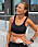 Pia Jensen, klädd i träningskläder, står lutad mot ett betongfundament och tittar ut i fjärran. På hennes bara mage syns en stomipåse.