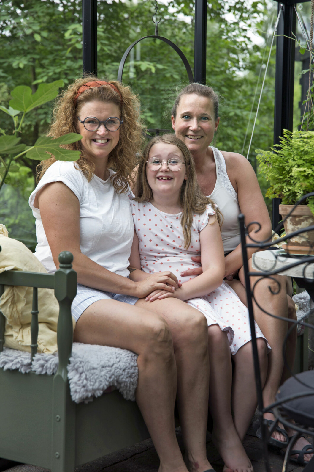 Pia Persson och Linda Hallin har skapat trädgården tillsammans. Här sitter de i det nybyggda växthuset tillsammans med minstingen Smilla. Pia Persson och Linda Hallin tillsammans med dotter Smilla.