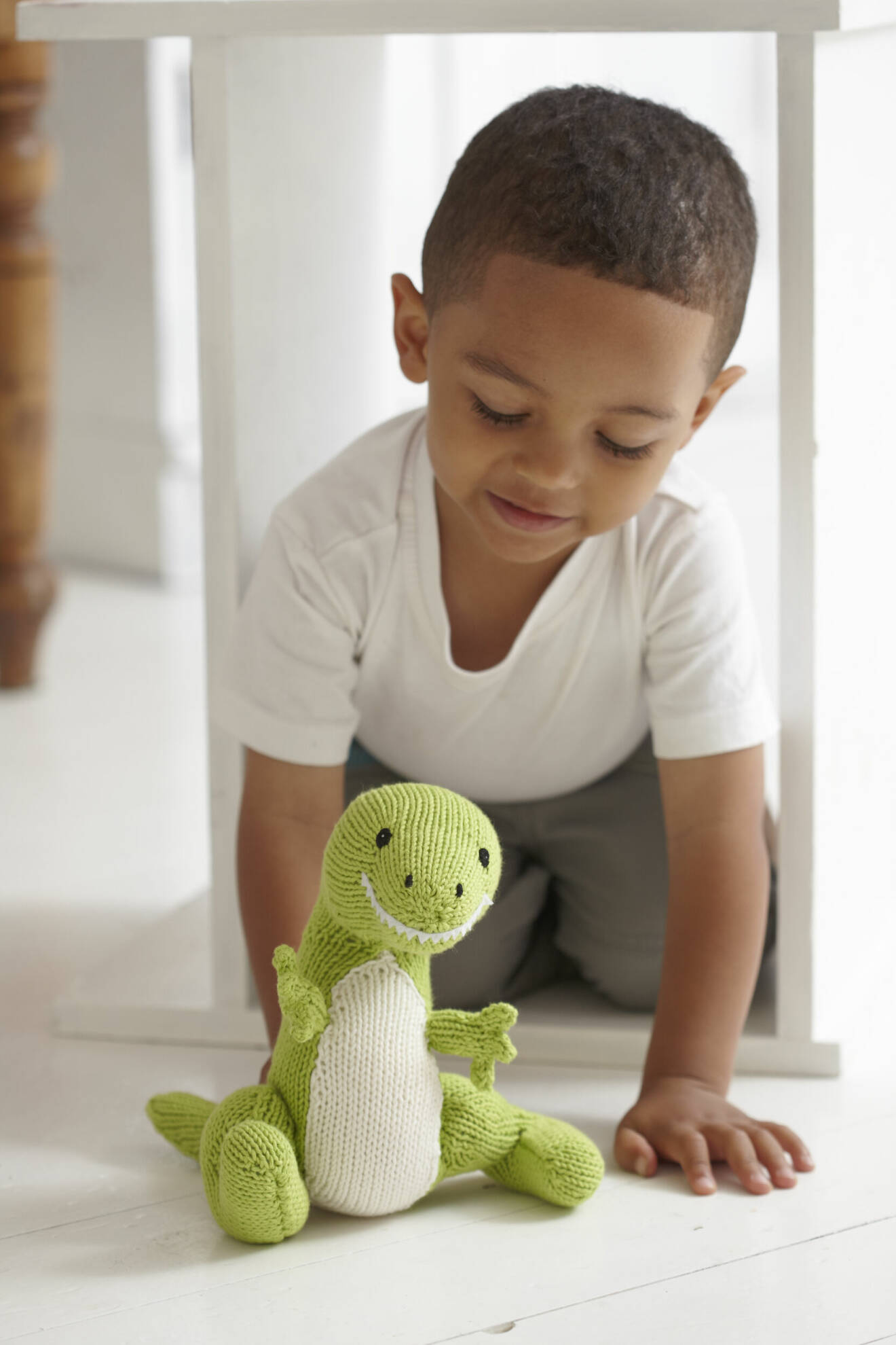 pojke med ett stickat gosedjur i form av en dinosaurie