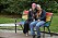 Polyamorösa paret Anna och Patrik sitter på en parksoffa som är målad i regnbådens färger.