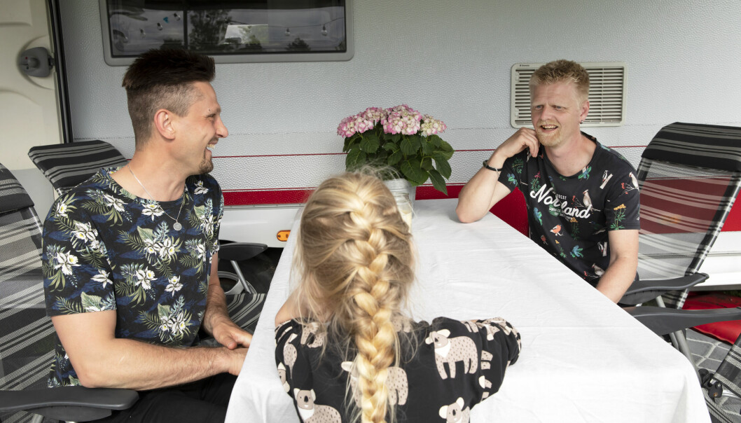 Hampus Engström och Erik Fridland sitter runt bordet utanför sin husvagn tillsammans med dottern Signe.