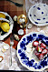 En blåvit tallrik med Baby Bell-ost på ett bord. På bordet syns också snäckor, en spetsduk och en citron.