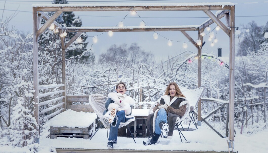 Sångerskorna Helen Sjöholm och Anna Stadling sitter i en pergola, täckt av snö och ljuskäglor.