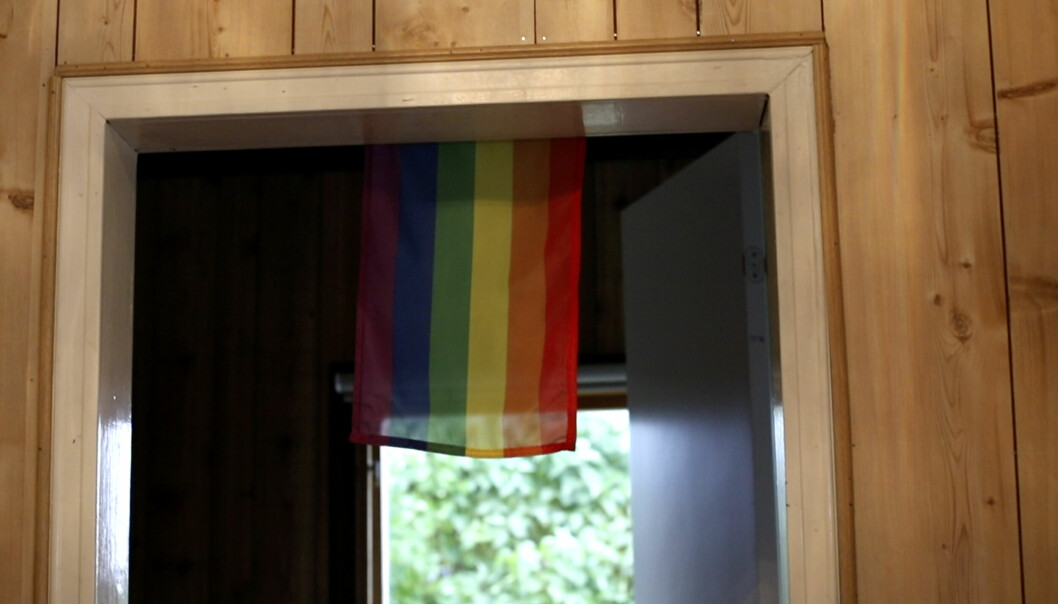 Prideflagga hänger ner framför dörrpost.