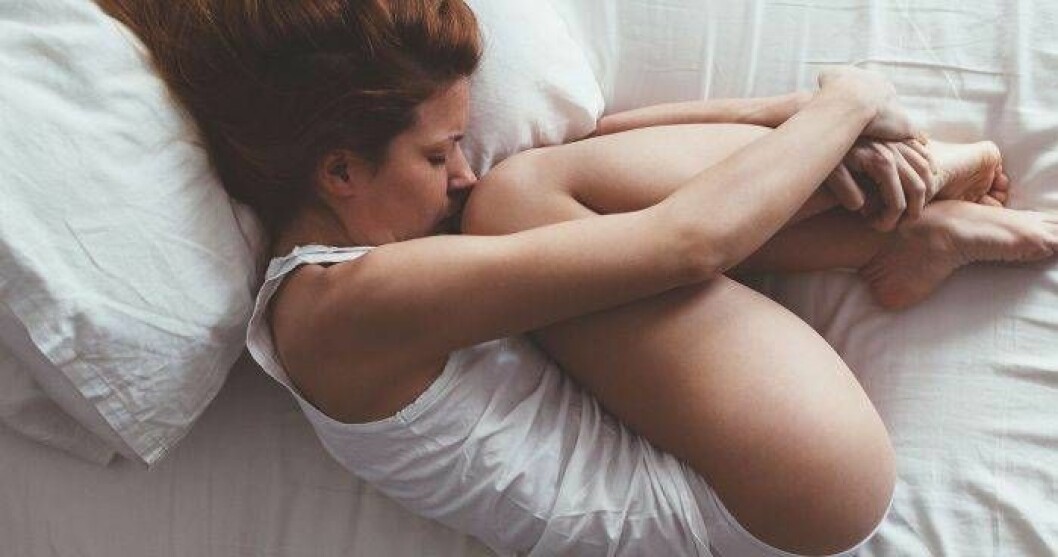 För många med proctalgia fugax kommer smärtan nattetid. Foto: Shutterstock/TT Kvinna med smärta som ligger i sin säng.