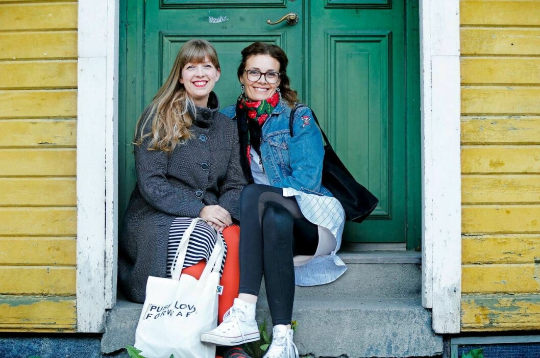 Illustratören Frida Hammar och meditationsledaren Annica Olofsson spånade fram en idé som bygger på värme, omtanke och vänliga handlingar. Lite inspiration fick de också från filmen Pay it forward. Illustratören Frida Hammar och meditationsledaren Annica Olofsson sitter framför ett färgglatt hus.
