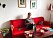Monica Galle sitter i en röd soffa och stickar i en lägenhet inredd i 1960-talsstil.