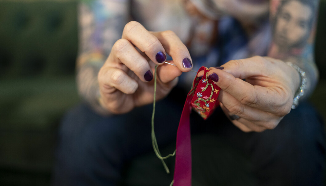 Operasångaren Rickard Söderberg broderar ett band till en folkdräkt.