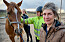 Maria tittar in i kameran. I bakgrunden syns en häst och hennes två väninnor.