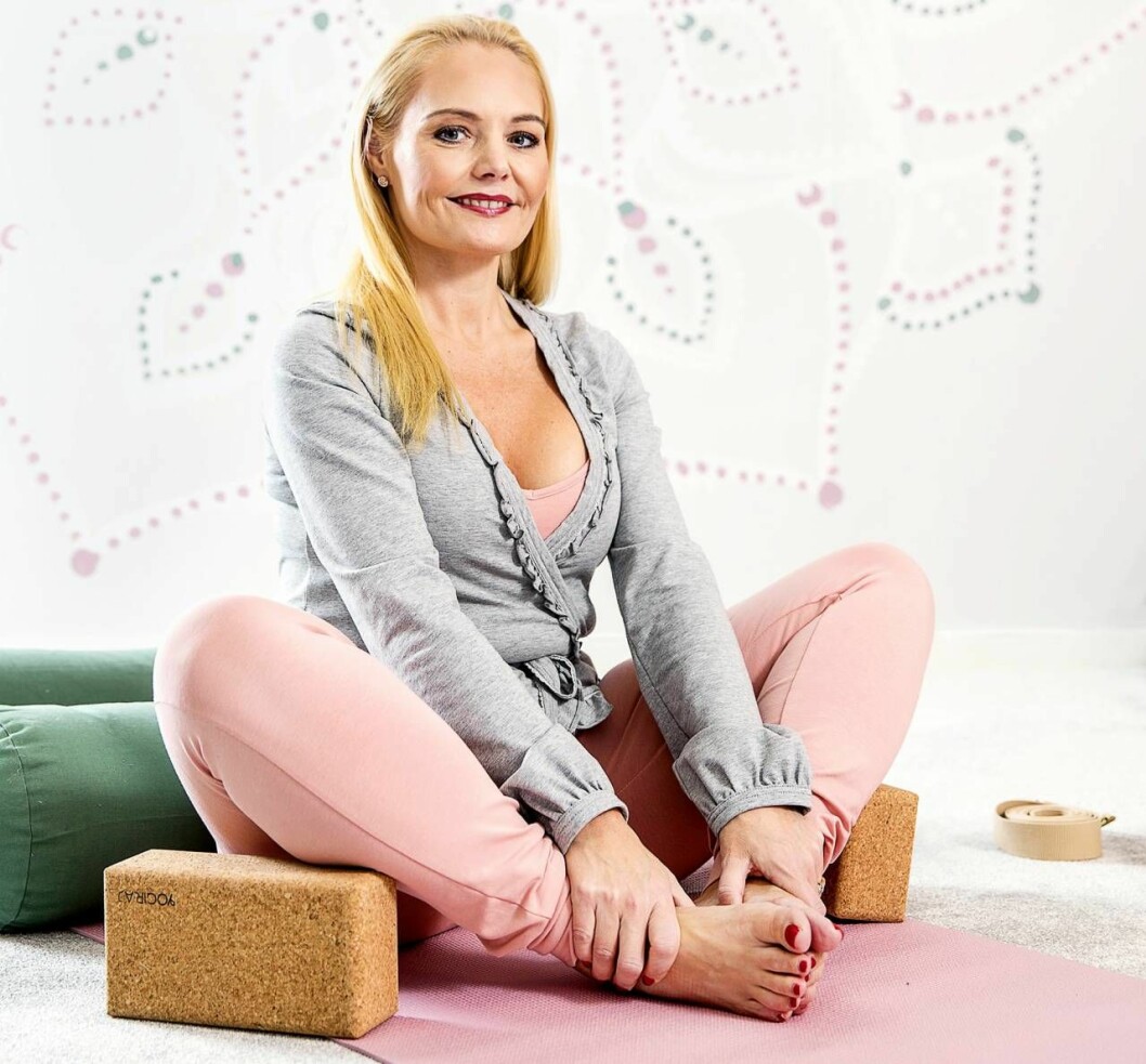Louise Hafdell sitter med benen i kors på en yogamatta
