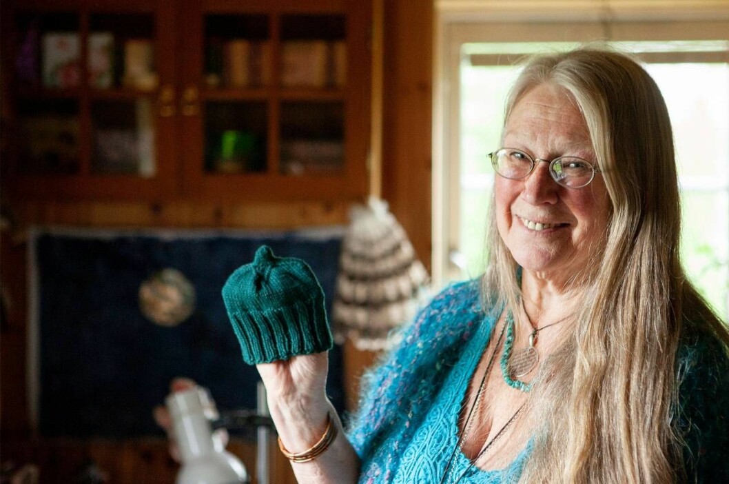 Sacha stickar bebismössor som skickas till barn i Afrika. Sacha visar upp en grön stickad babymössa.