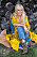 Sanne Salomonsen sitter lutad mot timmerstockar i gula och blå kläder.