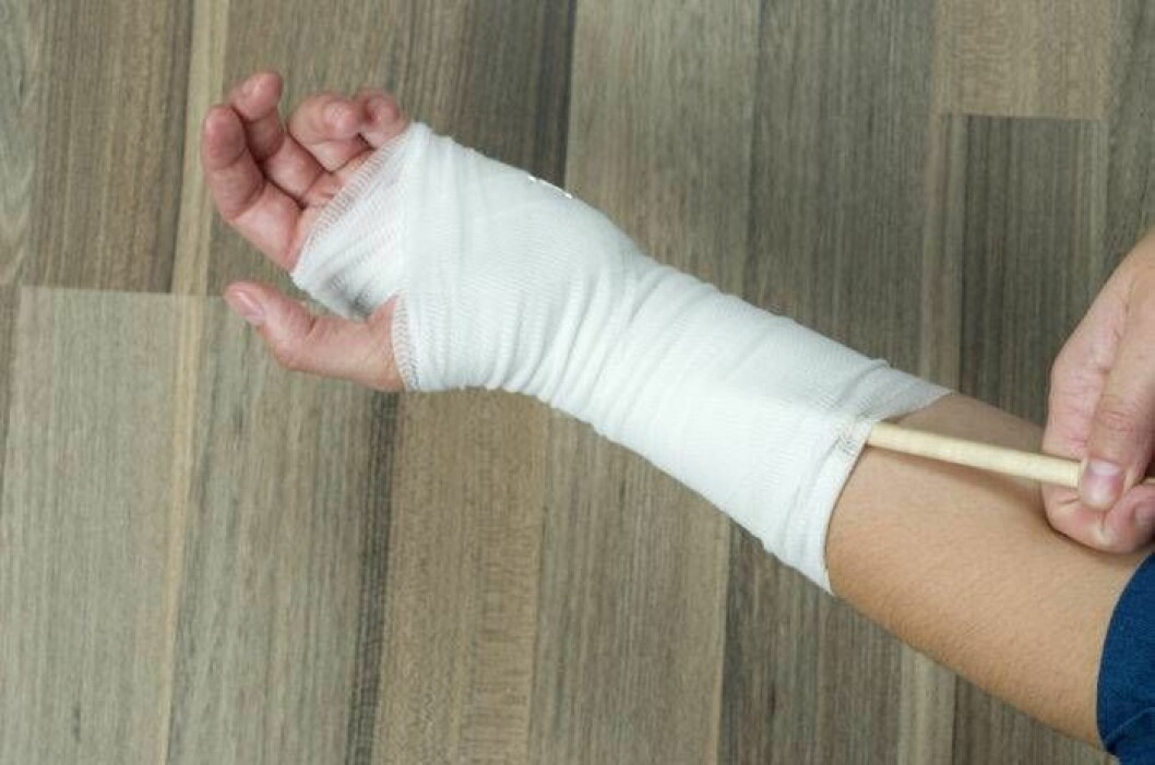 Man kliar sin inlindade arm med en träpinne