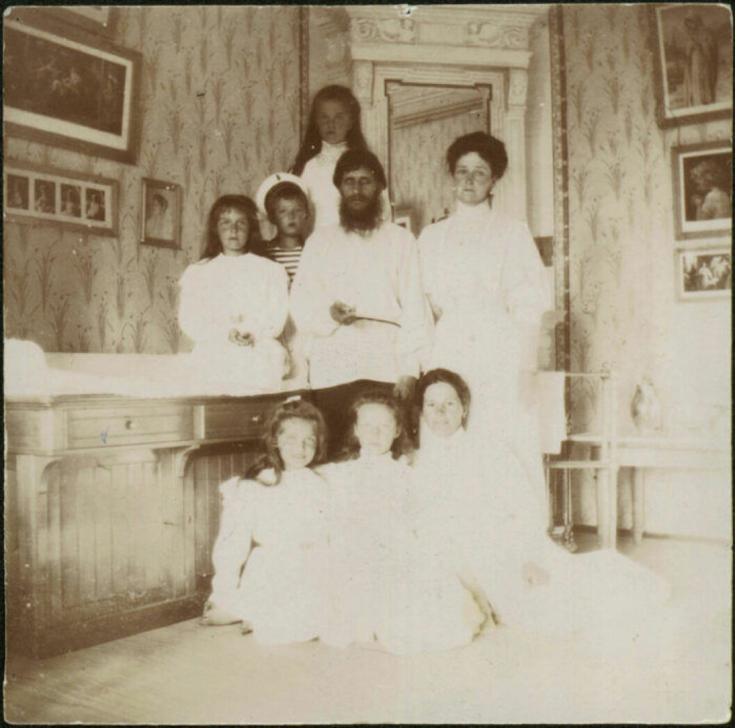 Grigorij Rasputin omringad av kejsarinnan Alexandra, hennes fyra barn samt barnens guvernant Maria Visnijakova.