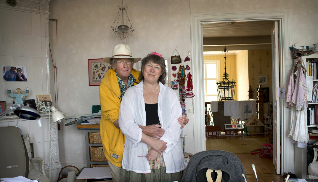 Konstnären Lena Linderholm och maken Gösta Linderholm i sitt hem i Strängnäs. Gösta håller om Lena framför henne målningar.