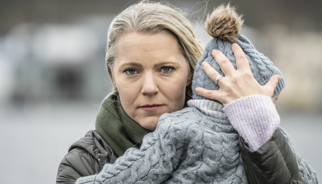 Porträttbild av Carina Bergfelt som tittar in i kameran, med sonen Hamilton i famnen, bortvänt från kameran.